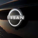 The emblem of a 2021 Nissan Ariya is shown at dusk.