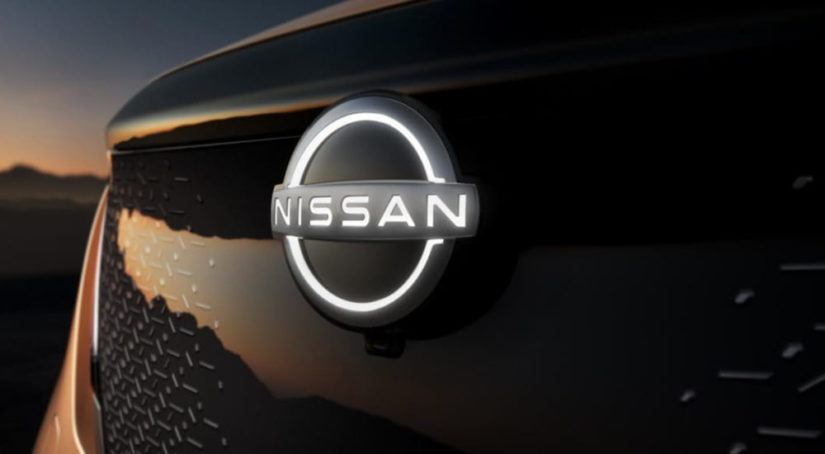 The emblem of a 2021 Nissan Ariya is shown at dusk.