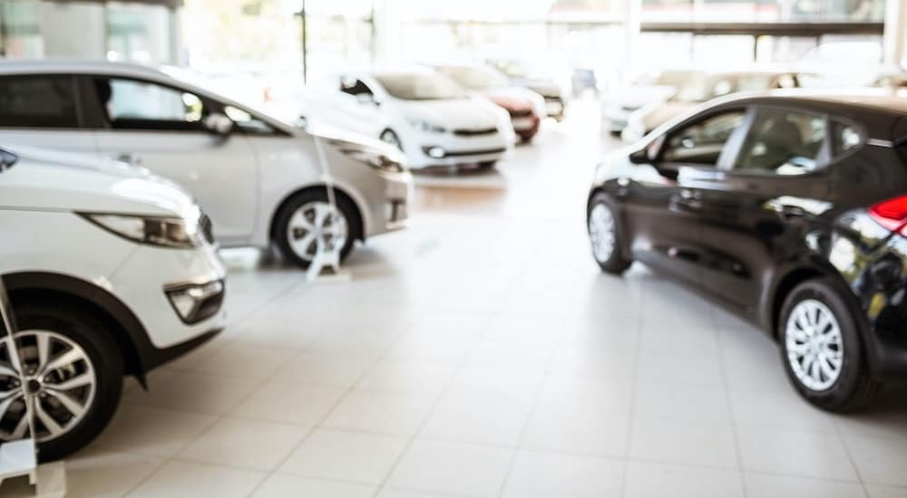 The inside of a car dealership is shown with a room full of cars.