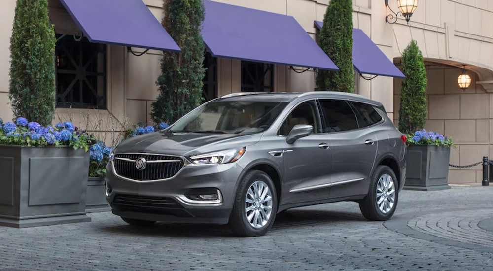 A grey 2020 Buick Enclave is shown from the side parked outside of a store front.