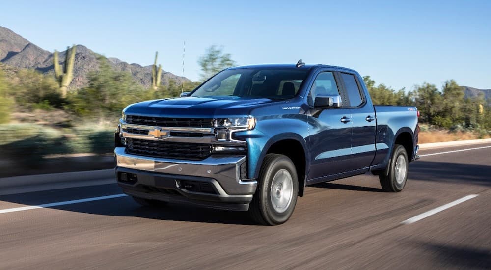 A blue 2019 Chevy Silverado 1500 is driving down a desert highway.