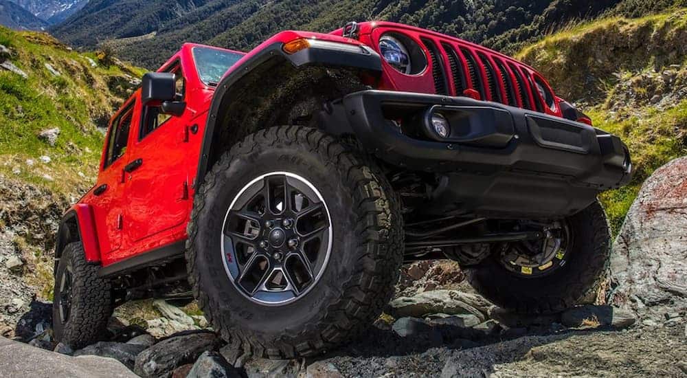 A red 2021 Jeep Wrangler Unlimited is parked on rocks on a mountain side.