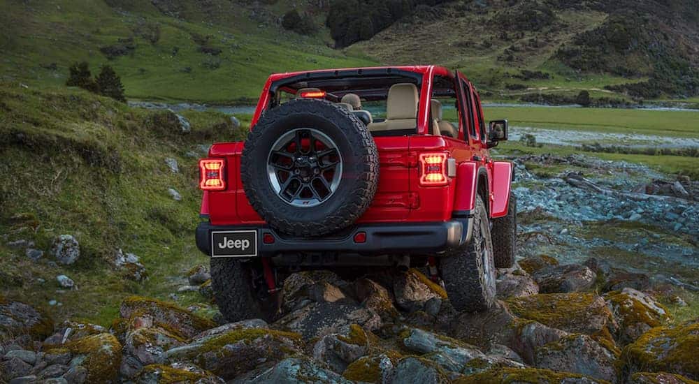 A red 2021 Jeep Wrangler Unlimited is shown from the rear on rocks. 