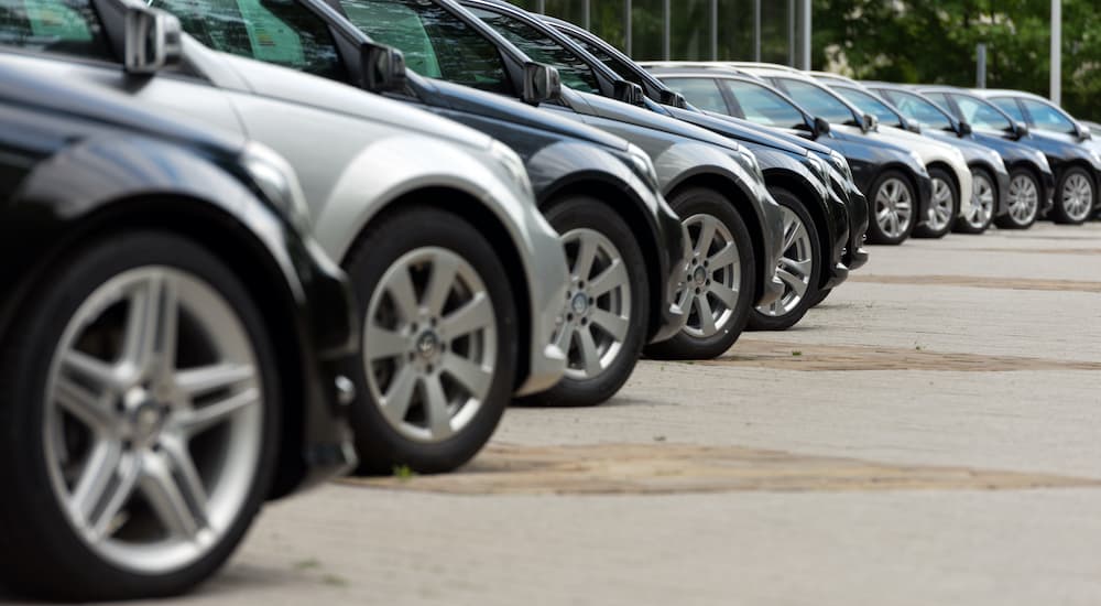 A row of cars are shown from a low angle at a used car dealership.