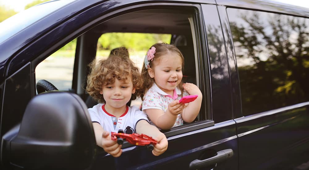 Two children are shown playing in the front seat of a minivan.