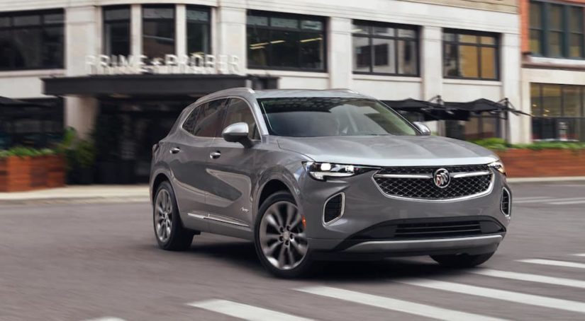 A grey 2021 Buick Envision is driving through a city street after winning a 2021 Buick Envision vs 2021 Hyundai Santa Fe comparison.