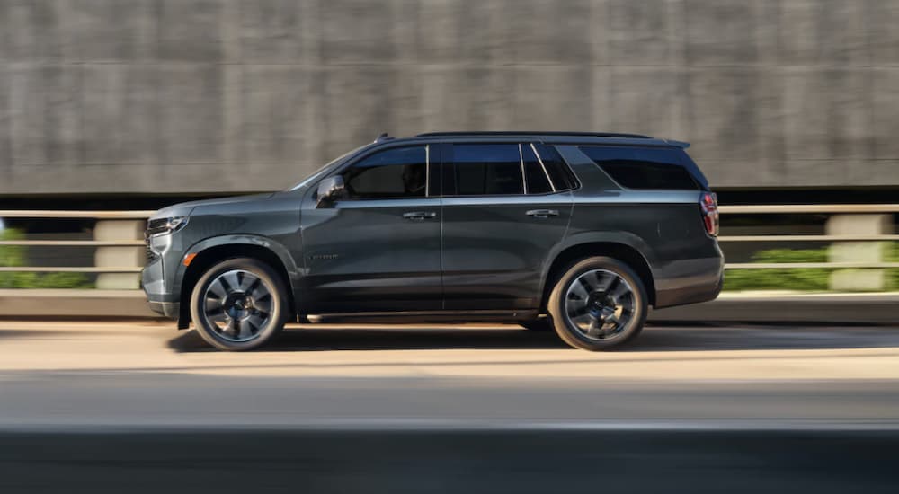 A grey 2021 Chevy Tahoe is shown from the side driving on a highway.