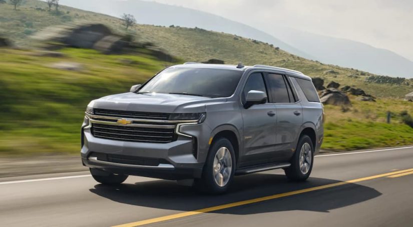 A grey 2021 Chevy Tahoe is shown from the side driving past a field.