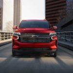 A red 2021 Chevy Tahoe is shown from the front driving on a highway.