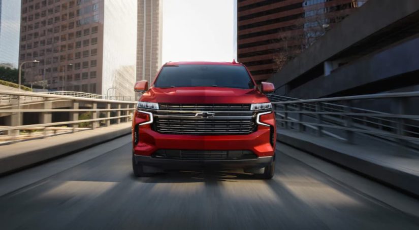 A red 2021 Chevy Tahoe is shown from the front driving on a highway.