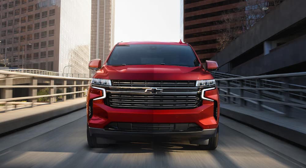 A red 2021 Chevy Tahoe is shown from the front driving through a city.