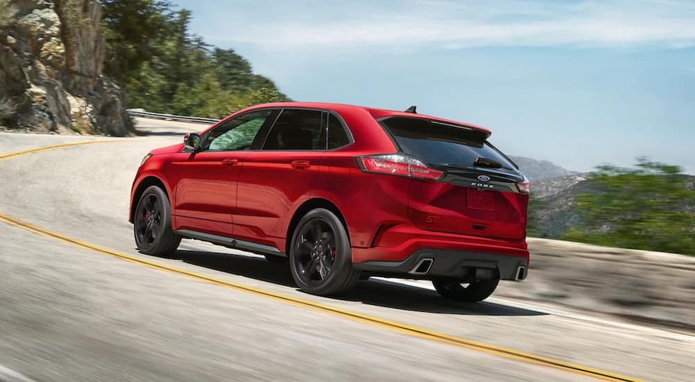 A red 2021 Ford Edge is driving down a two lane road next to a cliff.