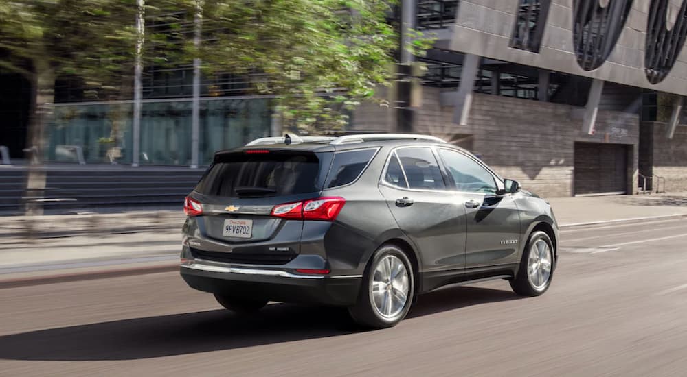 A grey 2021 Chevy Equinox is driving through a city.