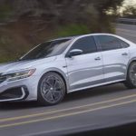 A silver 2021 Volkswagen Passat is shown from the side driving down a two way road.