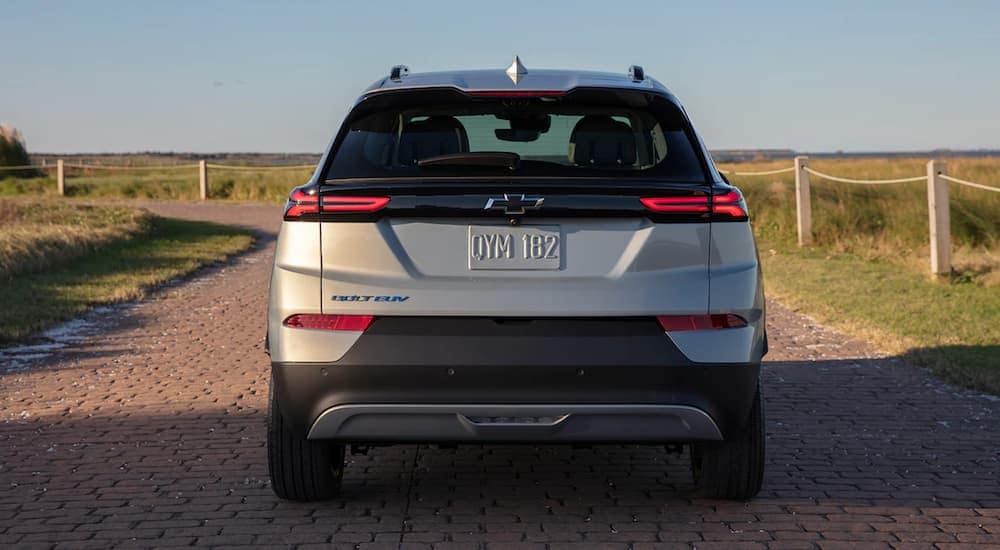 The rear of a tan 2022 Chevy Bolt EUV is parked near a beach.
