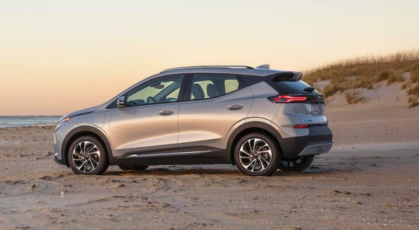 A silver 2022 Chevy Bolt EUV is parked on a beach at sunset.