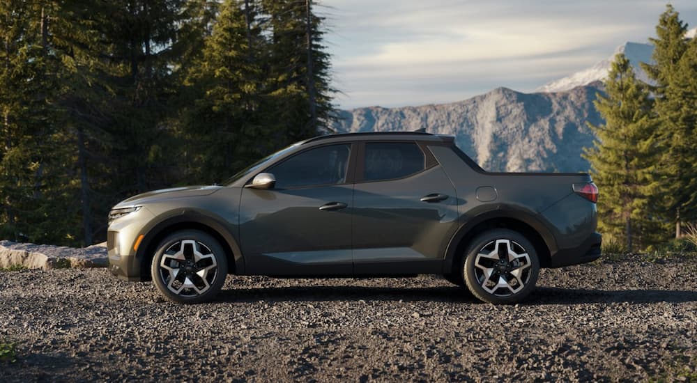 A green 2022 Hyundai Santa Cruz is shown from the side overlooking a mountain.