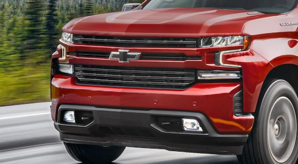The grille of a red 2021 Chevy Silverado 1500 is shown driving.