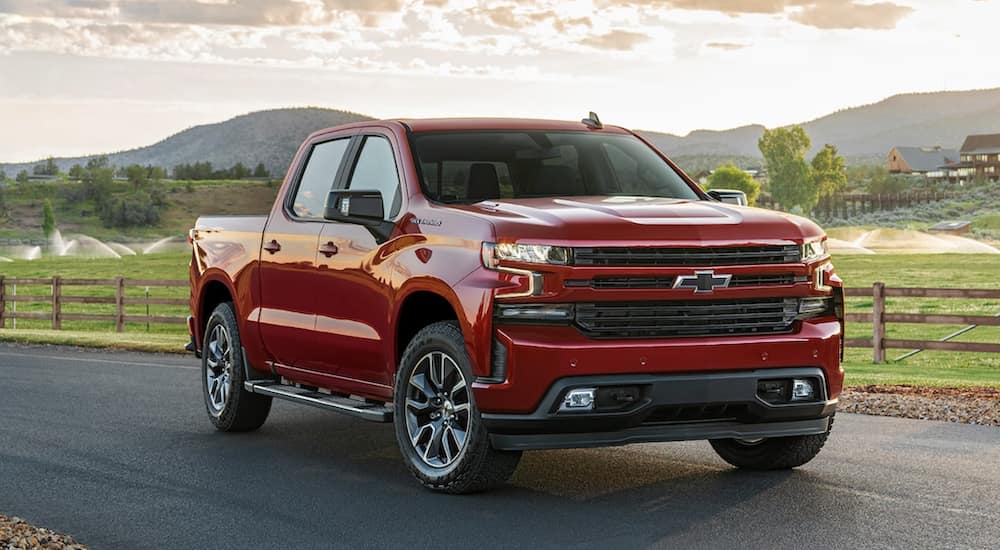 A red 2021 Chevy Silverado is parked next to a farm after leaving a Chevy Silverado dealer. 