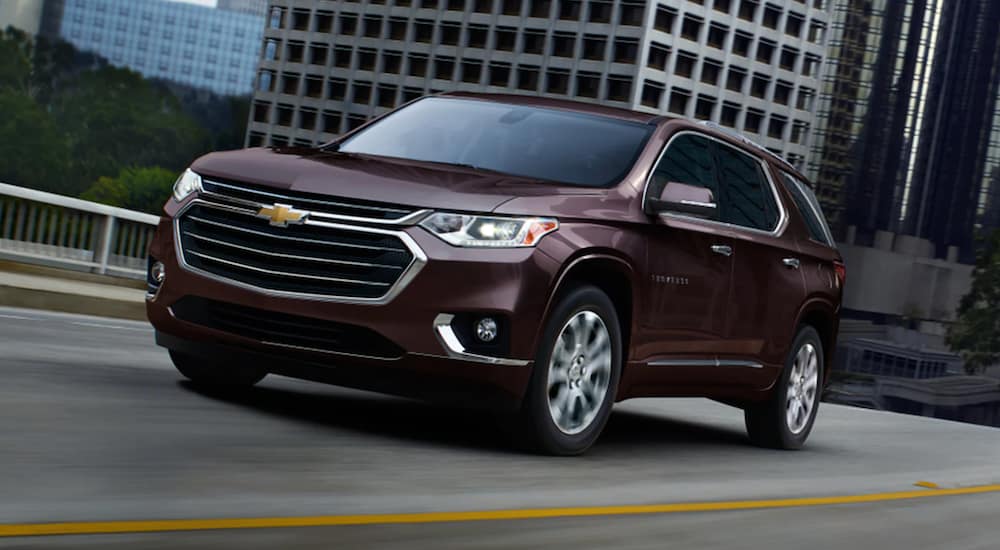 A maroon 2021 Chevy Traverse is driving through a city. 