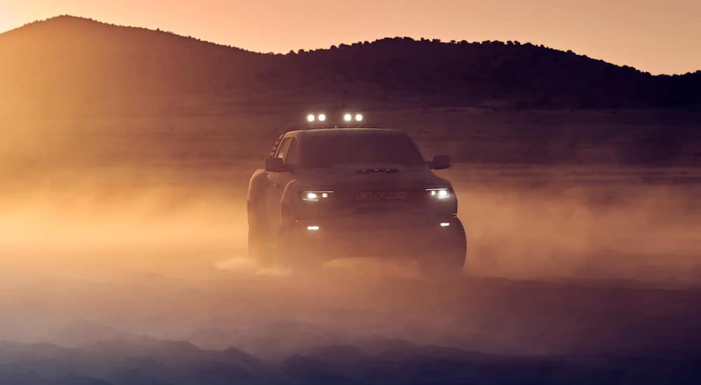 A tan 2021 Ram TRX is shown from the front parked in a desert at dusk.
