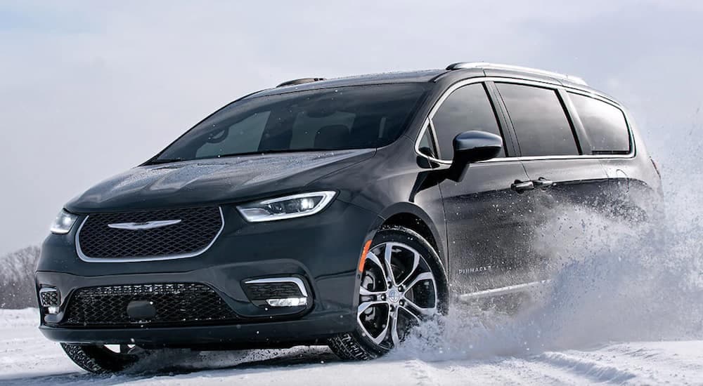 A black 2021 Chrysler Pacifica is driving through the snow.