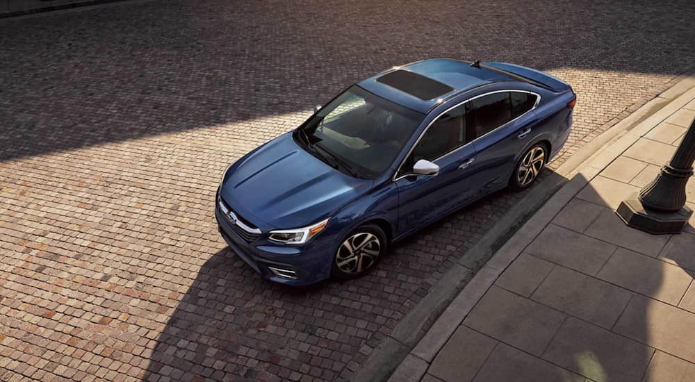 A blue 2021 Subaru Legacy is parked on a brick driveway.
