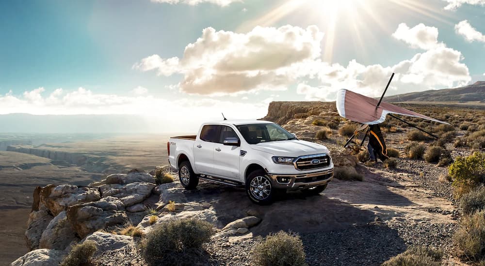 A white 2021 Ford Ranger Lariat SuperCrew is shown parked on a sunny day next to a hang glider.