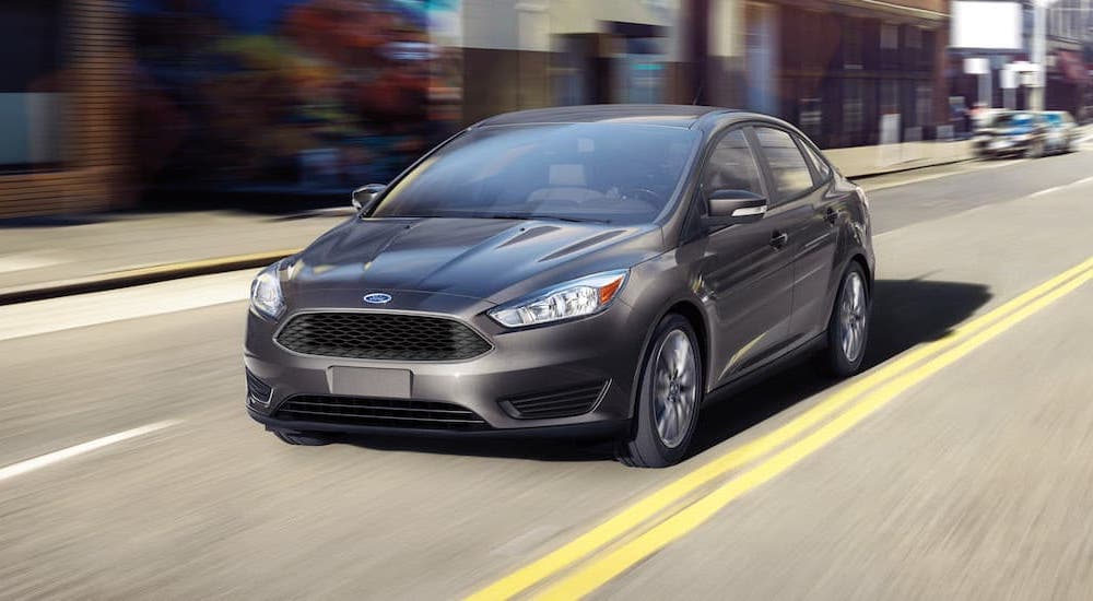 A silver 2016 Ford Focus is driving down a city street after leaving a used Ford Focus dealer.