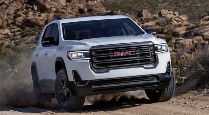 A 2020 GMC Acadia is shown from the front off-roading in the mountains after leaving a used GMC SUV dealer.