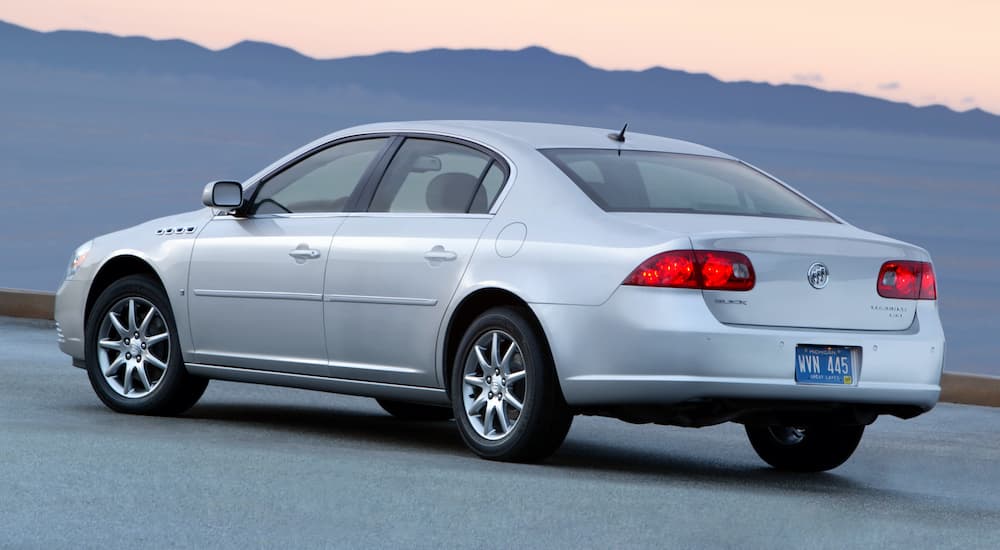 A silver 2010 Buick Lucerne CXL is parked in front of a mountain.
