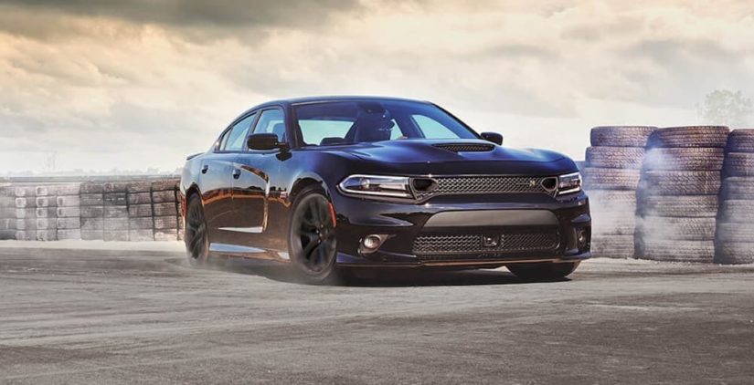 A black 2020 Dodge Charger is doing a burn out on a racetrack.