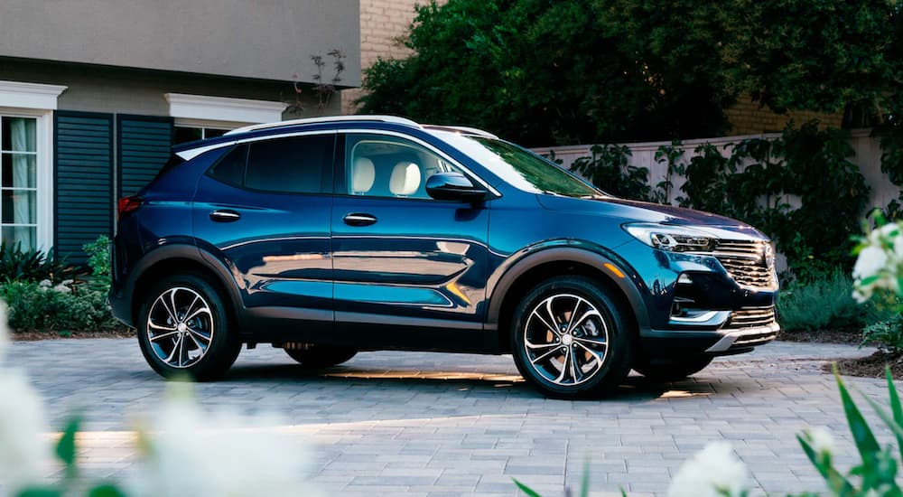 A blue 2021 Buick Encore GX is parked outside of a modern home.