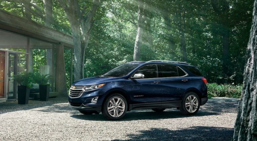 A blue 2021 Chevy Equinox is parked outside of a modern home in the forest.