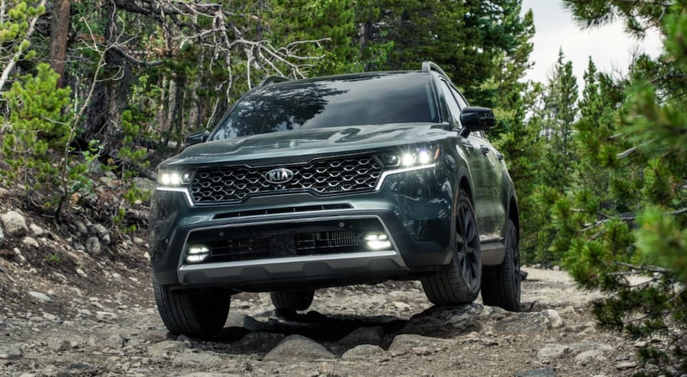 A green 2021 Kia Sorento is off-roading in the forest.