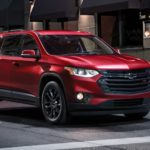 A red 2021 Chevy Traverse is shown driving through a city at night after wining a 2021 Chevy Traverse vs 2021 Ford Explorer comparison.
