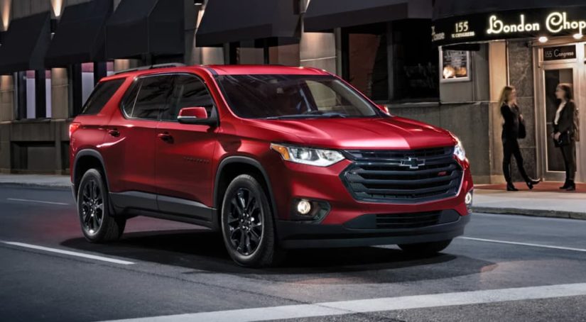 A red 2021 Chevy Traverse is shown driving through a city at night after wining a 2021 Chevy Traverse vs 2021 Ford Explorer comparison.