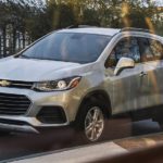 A white 2021 Chevy Trax is shown though a window parked on a city street.