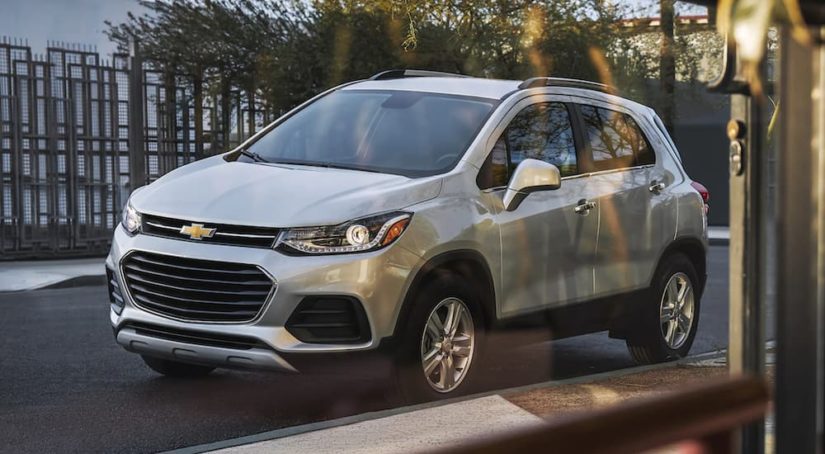 A white 2021 Chevy Trax is shown though a window parked on a city street.