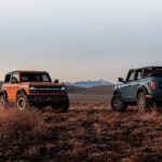 Two 2021 Ford Broncos are parked in a field at sunset after winning a 2021 Ford Bronco vs 2021 Jeep Wrangler comparison.