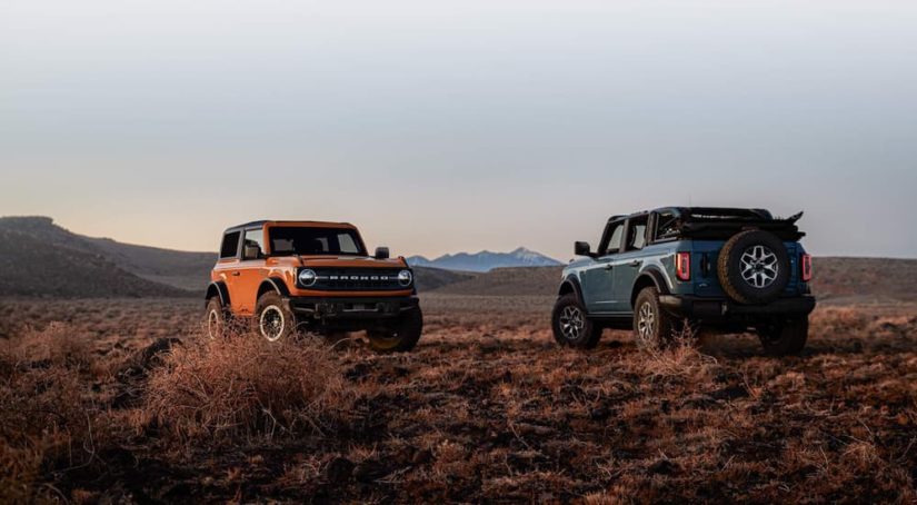 Two 2021 Ford Broncos are parked in a field at sunset after winning a 2021 Ford Bronco vs 2021 Jeep Wrangler comparison.