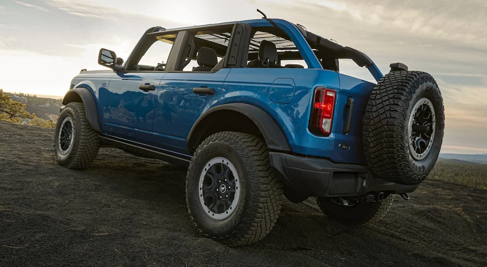 A blue 2021 Jeep Wrangler is shown parked in a field after winning a 2021 Ford Bronco vs 2021 Jeep Wrangler comparison.