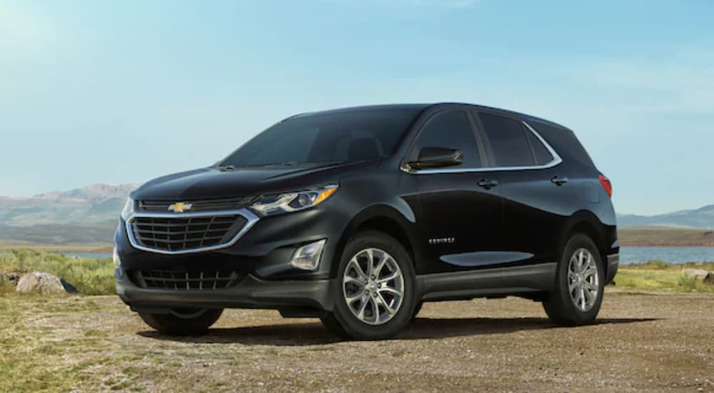 A black 2021 Chevy Equinox is shown parked in a dirt field in front of mountains.