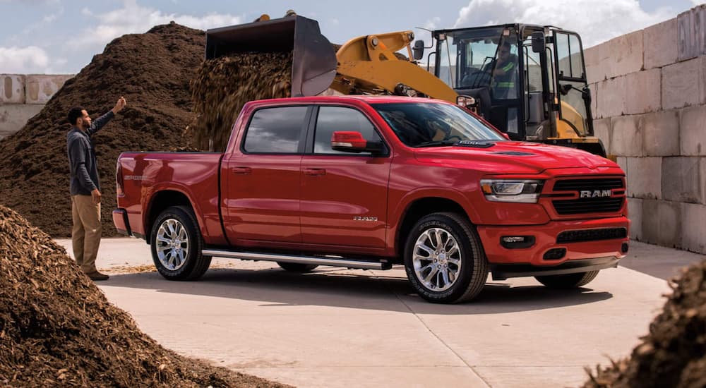 A red 2021 Ram 1500 is shown from the side while being used to move mulch at a construction site.