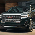 A black 2021 GMC Acadia is parked in front of a hotel after winning a 2021 GMC Acadia vs 2021 Chevy Traverse comparison.