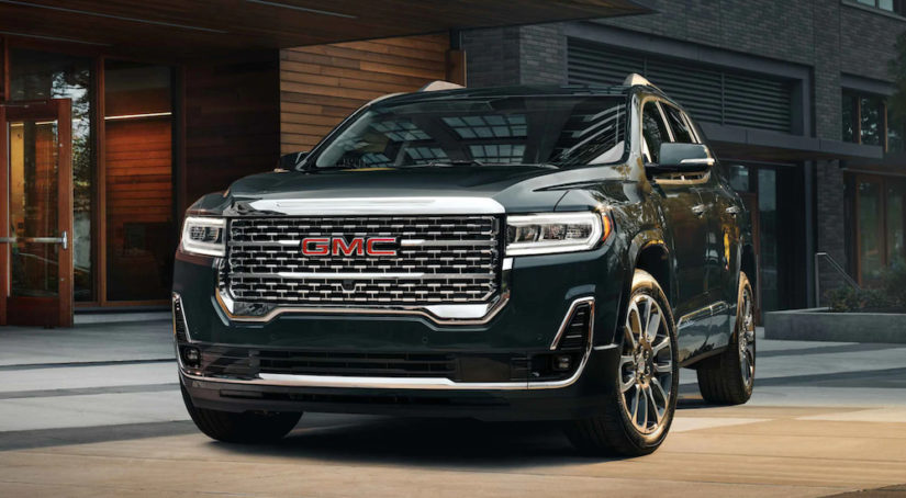 A black 2021 GMC Acadia is parked in front of a hotel after winning a 2021 GMC Acadia vs 2021 Chevy Traverse comparison.