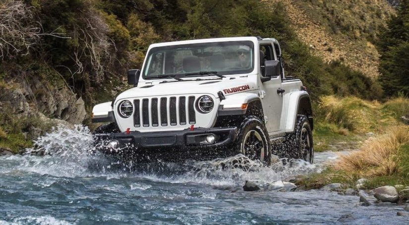 A white 2021 Jeep Wrangler Rubicon is shown driving through water after winning the 2021 Jeep Wrangler vs 2021 Ford Bronco shoot-out.