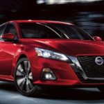 A red 2021 Nissan Altima is shown driving after winning a 2021 Nissan Altima vs 2021 Toyota Camry comparison.