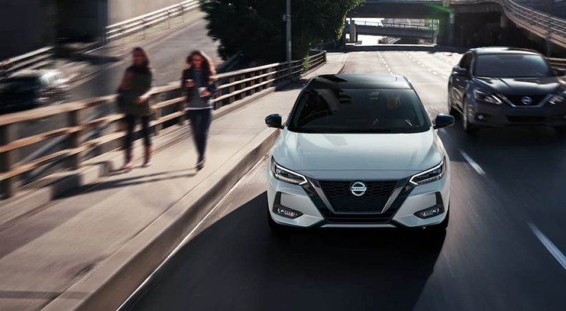 A white 2021 Nissan Sentra is shown from the front driving through a city.