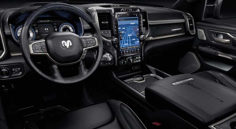 The interior of a 2021 Ram 1500 shows the steering wheel and infotainment screen.